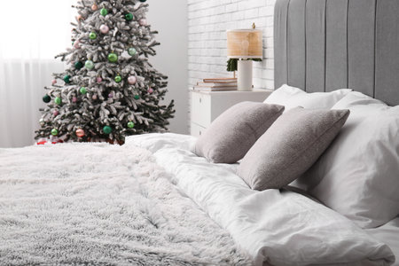 Bed with soft pillows in room decorated for Christmasの写真素材