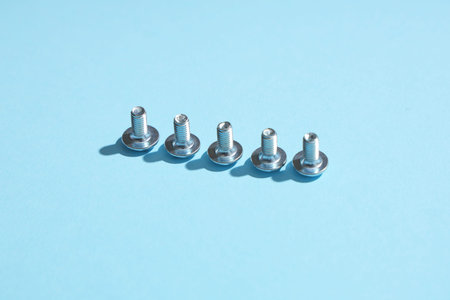 Row of tap bolts on blue background, closeup