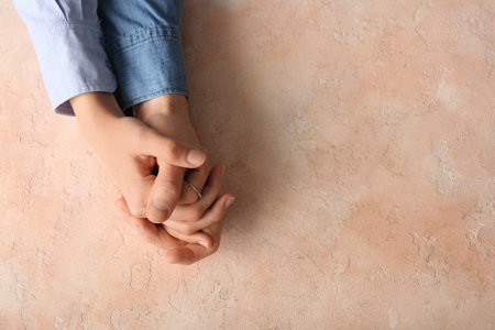 Couple holding hands on beige grunge background, top viewの写真素材