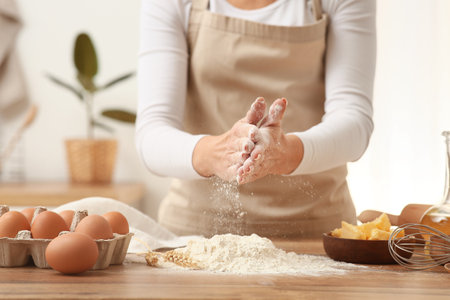 Woman preparing dough with ingredients on kitchen counterの写真素材