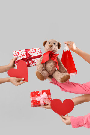 Female hands with toy bear, hearts and gifts on light background. Valentine's Day celebrationの写真素材