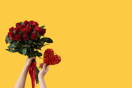 Woman holding roses with heart on yellow background. Valentine's Day celebrationの写真素材