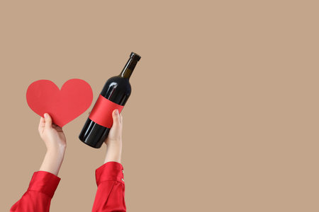 Woman holding wine bottle with heart on beige background. Valentine's Day celebrationの写真素材