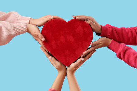 Female hands with heart-shaped gift box on blue background. Valentine's Day celebrationの写真素材