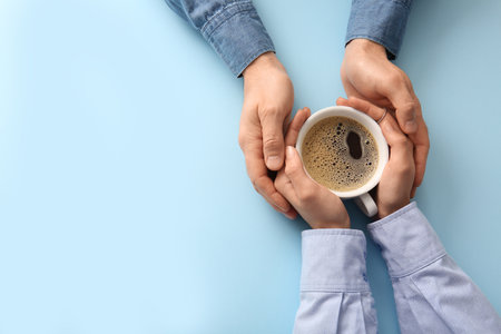 Hands of couple with coffee cup on blue background, top viewの写真素材