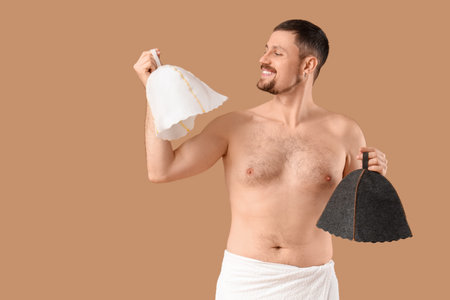 Handsome man with sauna felt hats on beige backgroundの写真素材