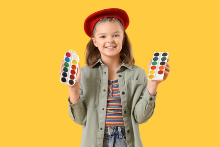 Cute artist with paints on yellow backgroundの写真素材
