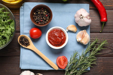 Composition with bowl of fresh tomato paste and aromatic spices on wooden tableの写真素材