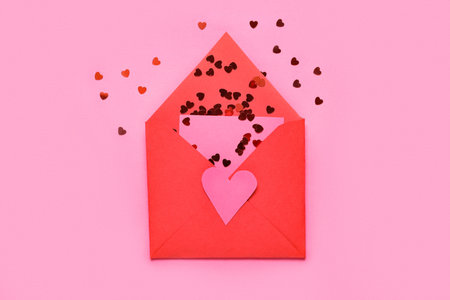 Envelope with card and heart-shaped sequins on pink background. Valentines Day celebration