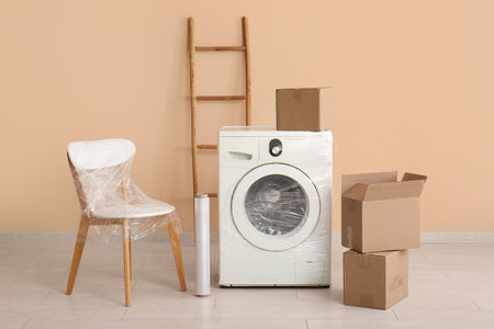 Wrapped chair and washing machine with stretch film in room on moving dayの写真素材