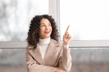 Young businesswoman pointing at something near window in officeの写真素材