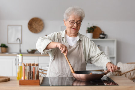 Senior woman frying vegetables in kitchenの写真素材