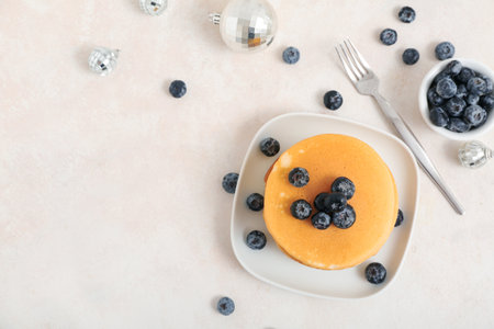 Plate of sweet pancakes with blueberries and Christmas disco balls on white backgroundの写真素材