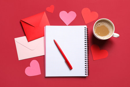 Envelopes with notebook, paper hearts and cup of coffee on red background. Valentine's day celebrationの写真素材