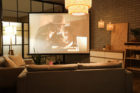 Interior of living room with projector screen, sofas and glowing lamps at night