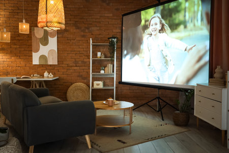 Interior of dark living room with projector screen, sofa and glowing lamps at nightの写真素材