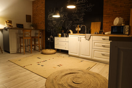 Interior of kitchen with white counters, chalkboard and glowing lamps in eveningの写真素材