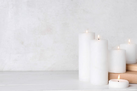Burning candles and books on white wooden tableの写真素材