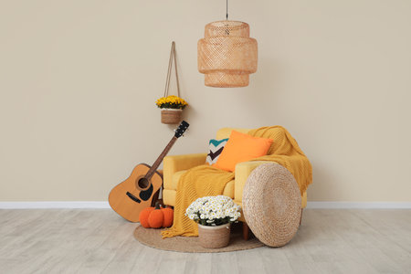 Beautiful autumn composition with armchair, guitar, pumpkin and beautiful chrysanthemum flowers in living roomの写真素材