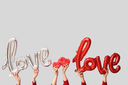Female hands with balloons in the shape of the word LOVE and gift boxes on white background. Valentine's Day celebrationの写真素材
