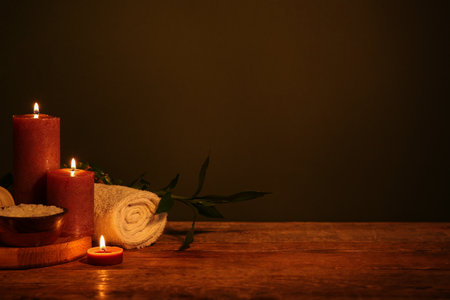 Composition with burning candles, sea salt, towel and bamboo stem on dark wooden tableの写真素材