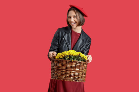 Stylish young woman with chrysanthemum flowers on red backgroundの写真素材