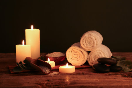 Spa composition with burning candles, sea salt and clean towels on dark wooden tableの写真素材