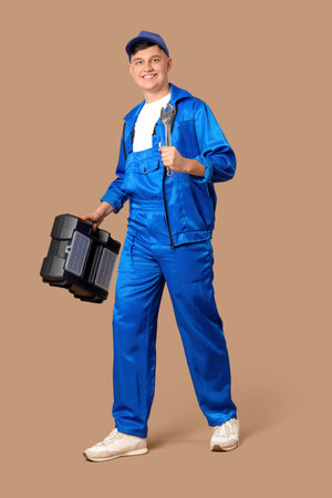 Male worker with wrench and kit on beige backgroundの写真素材