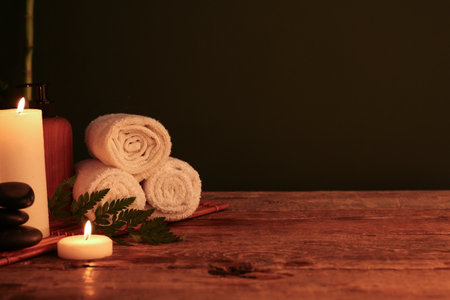 Composition with burning candles, clean towels and cosmetic product on dark wooden tableの写真素材