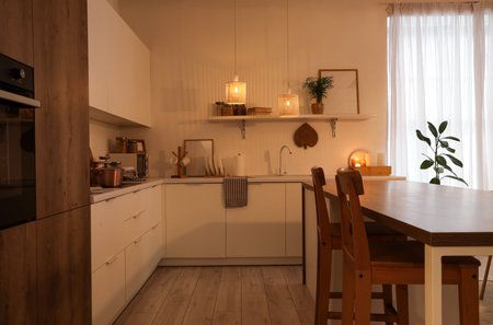 Interior of kitchen with shelf, counters and glowing lamps in eveningの写真素材