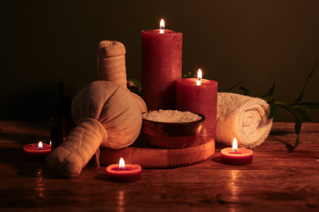Spa composition with herbal massage bags, burning candles and sea salt on dark wooden tableの写真素材