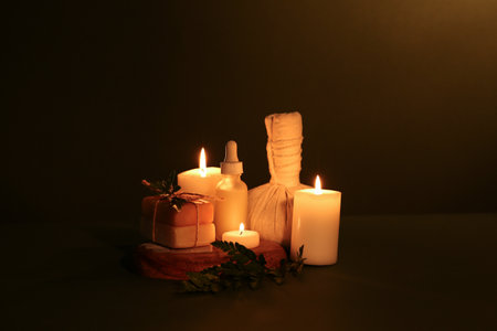 Spa composition with burning candles, massage bag and soap bars on dark color backgroundの写真素材