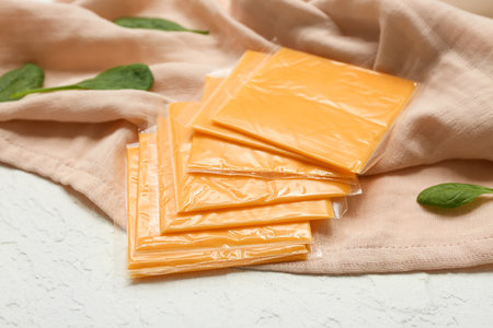 Slices of delicious processed cheese and fresh spinach on white grunge tableの写真素材