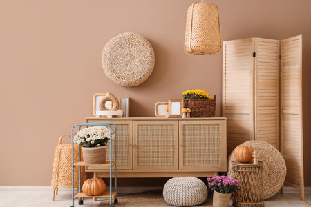 Chest of drawers, chrysanthemum flowers with autumn decor near beige wall in roomの写真素材