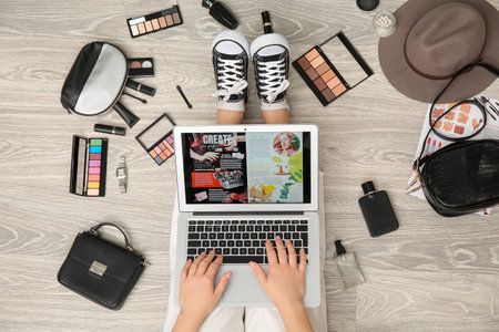 Woman using laptop for online shopping, stylish accessories and decorative cosmetics on light wooden floorの写真素材