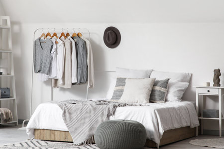 Rack with clothes and comfortable bed in interior of bedroomの写真素材