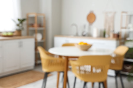 Blurred view of light kitchen with counters, shelf units and dining tableの写真素材