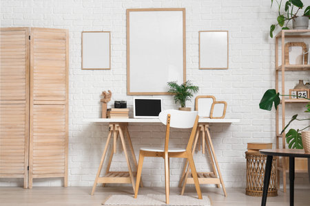 Blank posters and workplace with laptop in living room