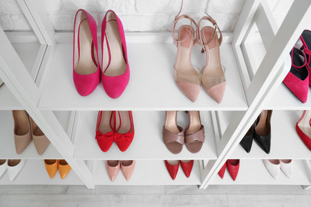 Shelves with stylish women's shoes near white brick wallの写真素材