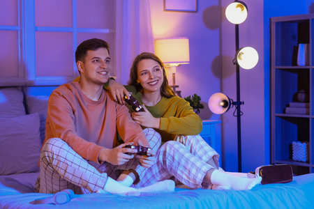 Young couple playing video game in bedroom at night