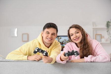 Young couple with game pads sitting on sofa at home