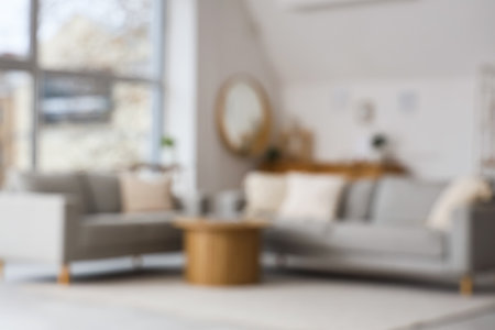 Blurred view of light living room with gray sofas and tableの写真素材