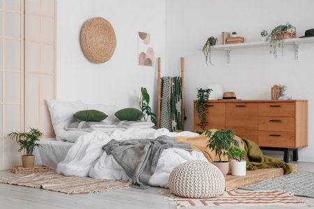 Interior of bedroom with bed, chest of drawers and houseplantsの写真素材