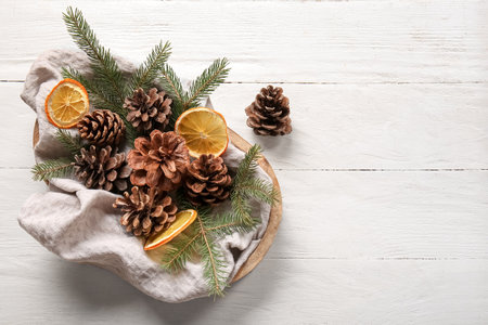 Tray with pine cones, fir branches and slices of dried orange on white wooden backgroundの写真素材