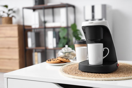 Coffee machine with cup and cookies on table in office, closeupの写真素材