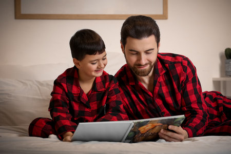 Father with his little son reading bedtime story on bed at homeの写真素材