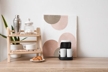 Modern coffee machine with cups, sugar and croissants on kitchen tableの写真素材