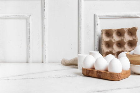 Wooden holder with raw chicken eggs on white background