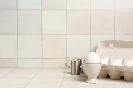 Holders with raw chicken eggs on white tile background