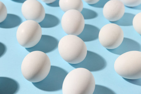 Many raw chicken eggs on blue background